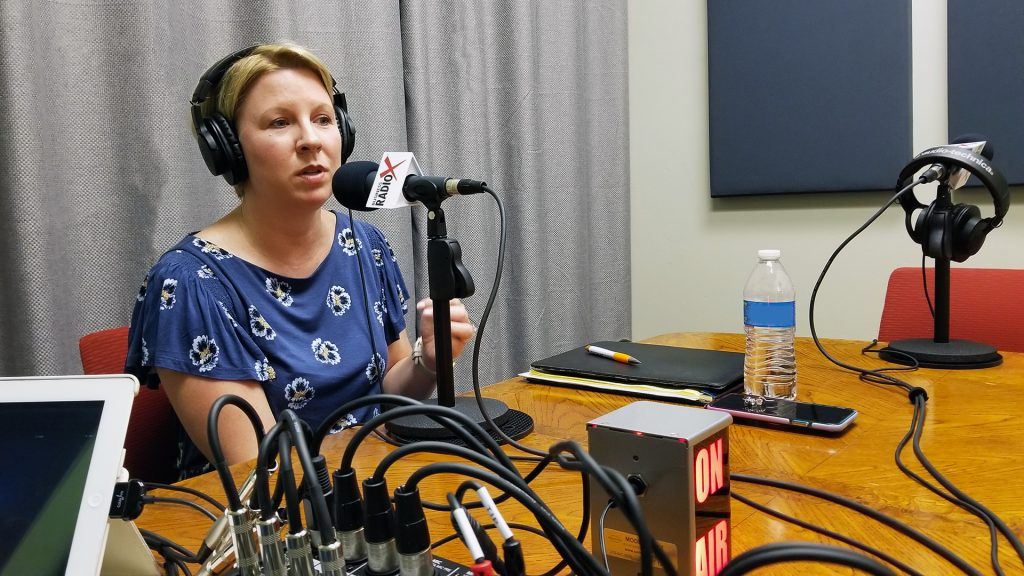 Jackie Wright with Rainmaker Integrated speaks into a microphone in the Valley Business RadioX studio in Phoenix, AZ